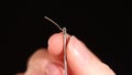 Thin thread going through a needle hole on black