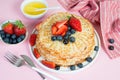 Thin traditional Russian pancakes on a trendy pink background with berries and honey. Horizontal photo, close- up Royalty Free Stock Photo