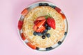 Thin traditional Russian pancakes on a trendy pink background with berries and honey. Horizontal photo, top view Royalty Free Stock Photo