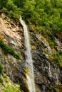 Thin water stream flowing from rocky slope of