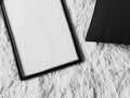 Thin wooden frame with blank copyspace as poster photo print mockup, black cushion pillow and fluffy white blanket, flat Royalty Free Stock Photo