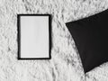 Thin wooden frame with blank copyspace as poster photo print mockup, black cushion pillow and fluffy white blanket, flat Royalty Free Stock Photo