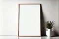 Thin wooden picture frame mockup stands on floor next to pot of green plant Royalty Free Stock Photo
