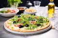 thincrust pizza with olives and arugula on a stone backdrop Royalty Free Stock Photo
