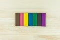 Things for the development of children`s abilities: 7 pieces of clay of different colors lie horizontally in a row wooden Desk