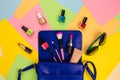 Things from open lady purse. Cosmetics and women`s accessories fell out of blue handbag on colourful background. Royalty Free Stock Photo