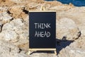 Think ahead symbol. Concept words Think ahead on beautiful black chalk blackboard on a beautiful beach stone background. Business