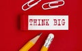 THINK BIG message written on torn red paper with pencils and clips, business Royalty Free Stock Photo