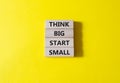 Think big start small symbol. Concept words Think big start small on wooden blocks. Beautiful yellow background. Business and Royalty Free Stock Photo