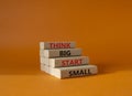 Think big start small symbol. Concept words Think big start small on wooden blocks. Beautiful orange background. Business and Royalty Free Stock Photo