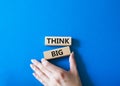 Think big symbol. Wooden blocks with words Think big. Beautiful blue background. Businessman hand. Business and Think big concept Royalty Free Stock Photo