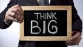 Think big written on blackboard, male in suit holding sign, motivational concept Royalty Free Stock Photo