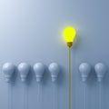 Think different concept One glowing light bulb standing out from the dim or unlit white lightbulbs on white wall background
