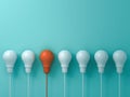 Think different concept One hanging orange light bulb standing out from the white light bulbs on blue pastel color wall backgroun Royalty Free Stock Photo