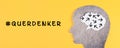 Think different stands in german language on the yellow background, head with brain, being a nonconformist, standing out