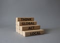 Think global act local symbol. Wooden blocks with words Think global act local. Beautiful grey background. Business and Think