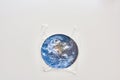 Think globally, act locally. Conceptual flatlay with polyethylene plastic disposable bag covering Earth made of paper