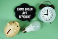 Think Green. Act Efficient with light bulb, piggy bank and alarm clock on green background Royalty Free Stock Photo