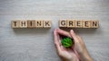 Think green phrase made of cubes, woman holding plant in hands, greenhouse gases