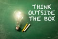 Think Outside the Box. Light bulb on a green chalk board Royalty Free Stock Photo