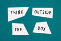 Think outside the box is standing on pieces of white paper, petrol colored background, brainstorming Royalty Free Stock Photo