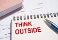 THINK OUTSIDE text written on notepad with pen on financial documents Royalty Free Stock Photo