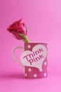 Think pink message written on a white heart sign on a pink polka dot coffee mug