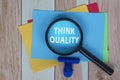 Think Quality on Colorful Adhesive Note With Magnifying Glass. Business concept.