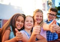 We think youre awesome. Portrait of a group of young children showing thumbs up outside.