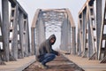 Thinker sad teenager in depression sitting crouched on the bridge at the sunset and looking true camera. Concept of teenage Royalty Free Stock Photo