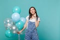 Thinkful young woman in denim clothes looking up put hand prop up on chin celebrating hold colorful air balloons