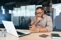 Thinking African American businessman reading news on smartphone, man working inside office at work using laptop, worker Royalty Free Stock Photo