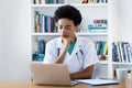 Thinking afro american female doctor at computer Royalty Free Stock Photo