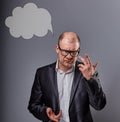 Thinking bald business man in eyeglasses and suit discussing and have an idea on grey background with empty cloud above the head.