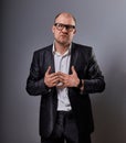 Thinking bald business man holding the chest two hands with serious face in eyeglasses in suit on grey background. Closeup
