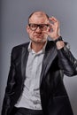 Thinking bald business man looking suspicious in eyeglasses in suit on grey background. Closeup