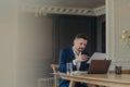 Thinking business executive sitting at his desk in front of laptop and analyzing documents Royalty Free Stock Photo