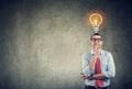 Thinking business man looking up at bright light bulb above head Royalty Free Stock Photo