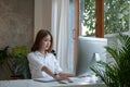 Thinking about business. Thoughtful young woman looking at computer screen while sitting at his working place at home Royalty Free Stock Photo