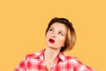 Woman with questioning expression looking up on yellow background