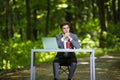 Thinking Businessman with hands on chin sitting at the office desk work at laptop computer and cup of coffee on road of green fore Royalty Free Stock Photo