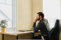 Thinking businessman sitting at office with documents, tablet on table.