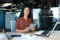 Thinking businesswoman with tablet computer looking seriously at camera, Hispanic woman working inside modern office Royalty Free Stock Photo
