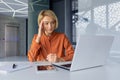 Thinking businesswoman working on laptop inside office, boss working sitting at table, female employee pondering Royalty Free Stock Photo