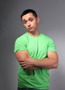 Thinking casual doubt young man with folded arms in green shirt on grey backgrond Royalty Free Stock Photo