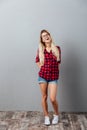 Thinking cheerful young blonde woman standing isolated