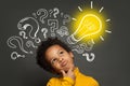 Thinking child boy on black background with light bulb and question marks. Brainstorming and idea concept Royalty Free Stock Photo