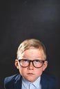 Thinking child. Portrait of smart school child with thumb up near blackboard blank and looking at camera. Happy kid boy Royalty Free Stock Photo