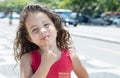 Thinking child in a red shirt outside in the city