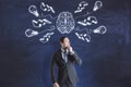 Thinking concept with pensive businessman on blackboard background with handwritten by chalk sketch of human brain, lightning Royalty Free Stock Photo